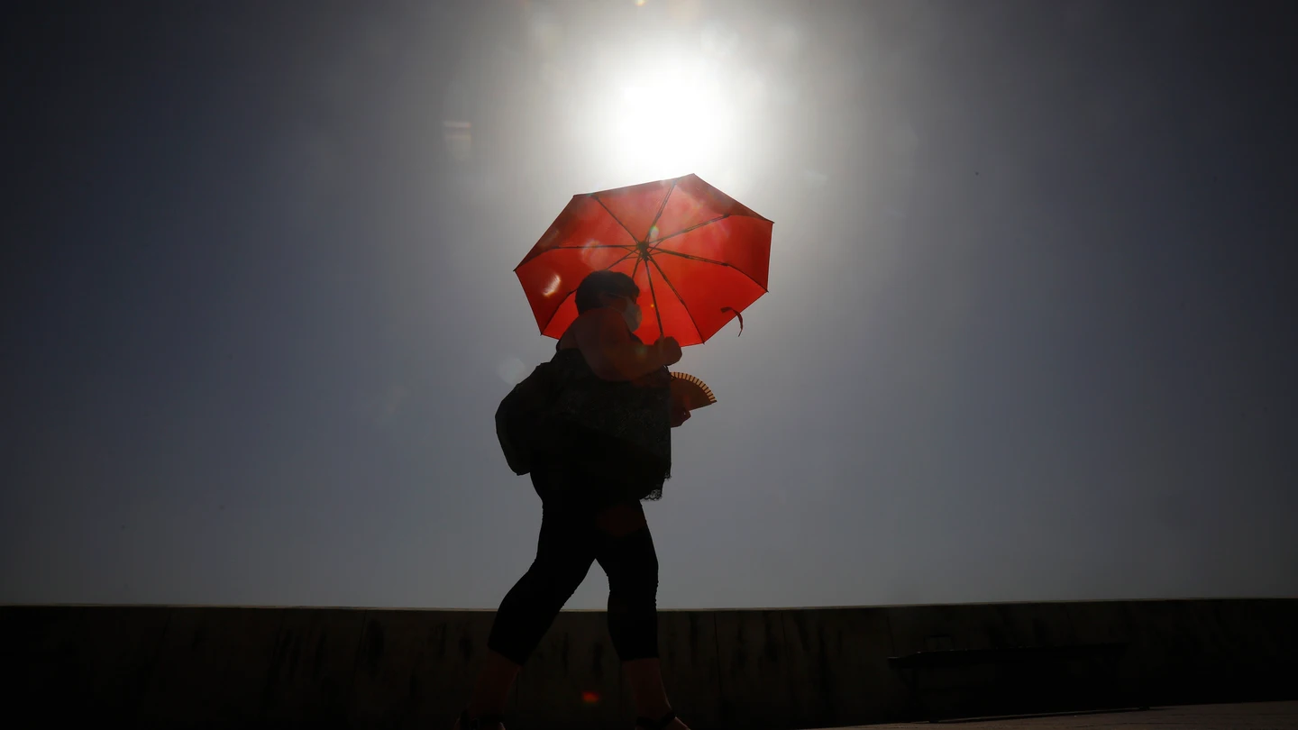 Una mujer camina resguardándose del sol con una sombrilla en Córdoba. Una mujer camina resguardándose del sol con una sombrilla en Córdoba.