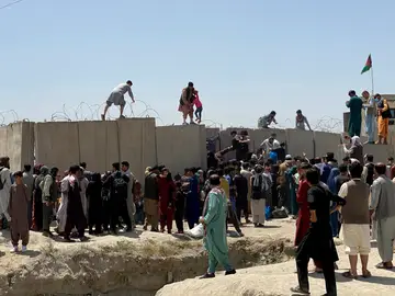 Afganos se agolpan a lo largo del muro del aeropuerto de Kabul en un intento de abandonar el país