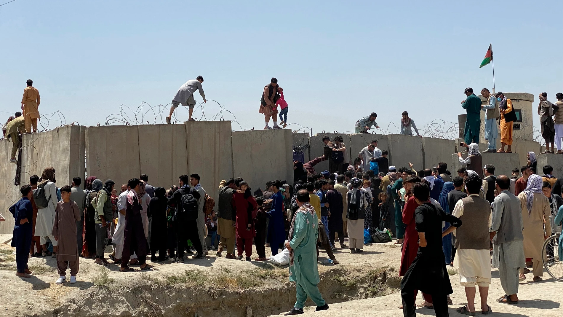 Afganos se agolpan a lo largo del muro del aeropuerto de Kabul en un intento de abandonar el país