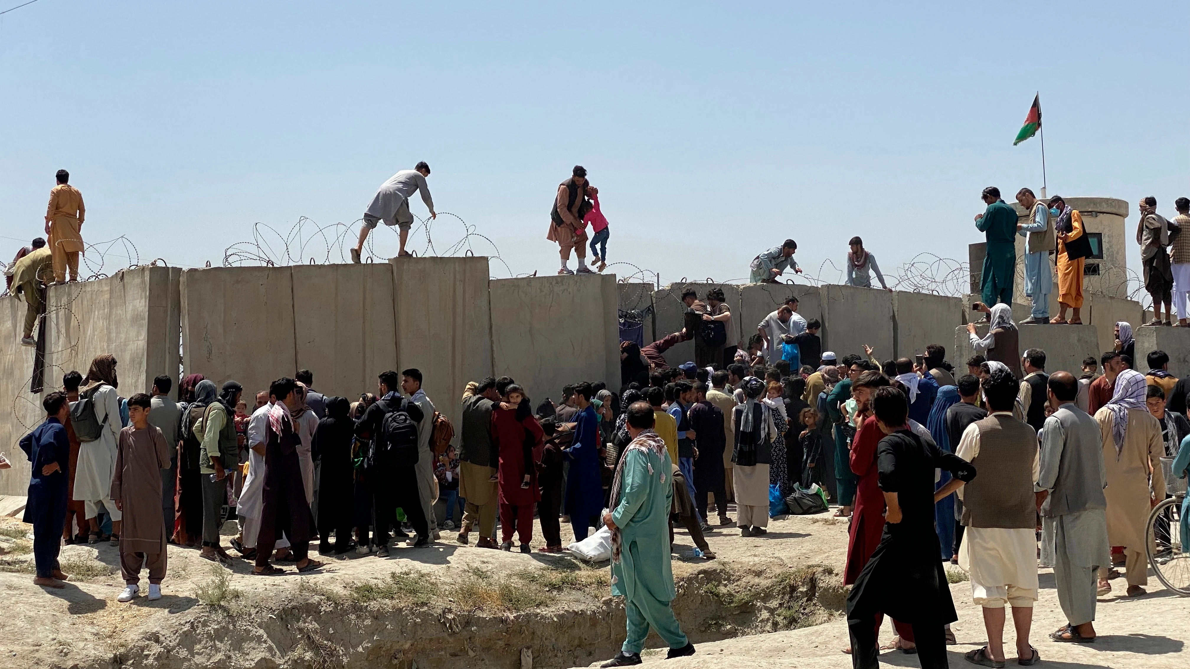 Afganos se agolpan a lo largo del muro del aeropuerto de Kabul en un intento de abandonar el país