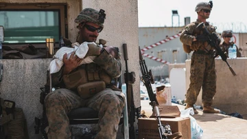 El sargento Isaiah Campbell sostiene al bebé tras recogerlo del muro del aeropuerto de Kabul.