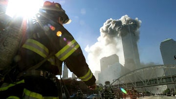 Los bomberos caminan hacia una de las torres antes del colapso tras el impacto de un avión el 11S