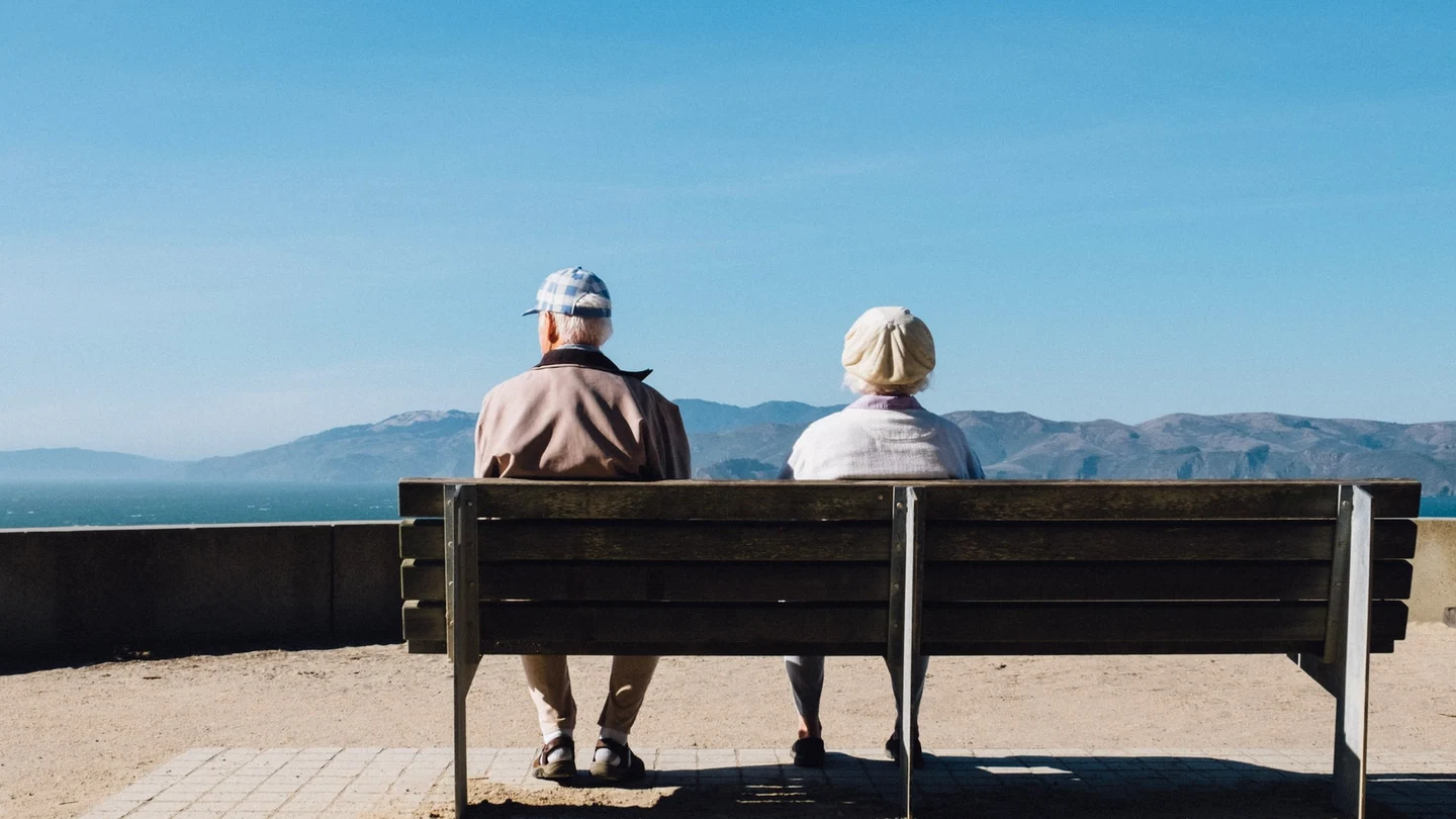 Dos ancianos sentados en un banco mirando hacia el horizonte costero Dos ancianos sentados en un banco mirando hacia el horizonte costero