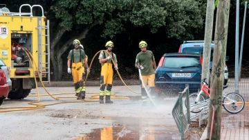 Miembros del IBANAT limpian las calles del fango acumuolado tras el desbordamiento del torrente. 