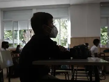 Un niño con mascarilla en un aula. 