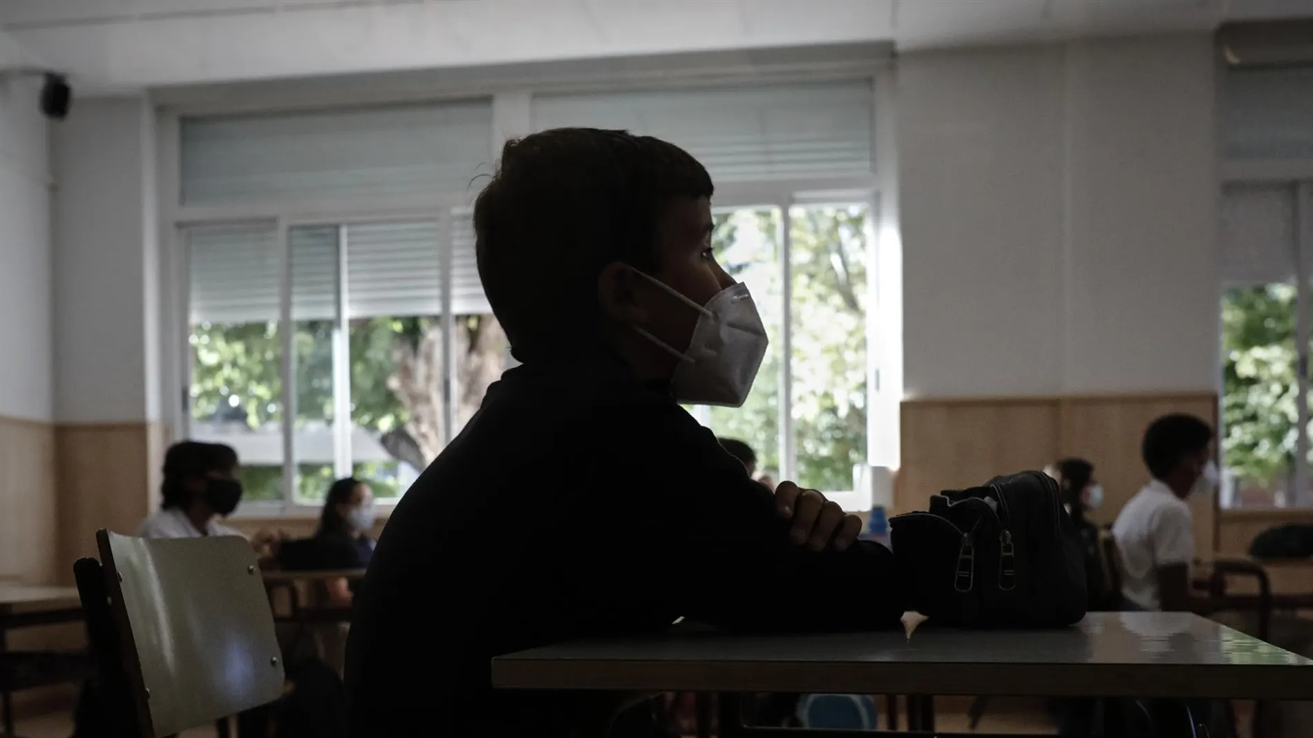 Un niño con mascarilla en un aula. 