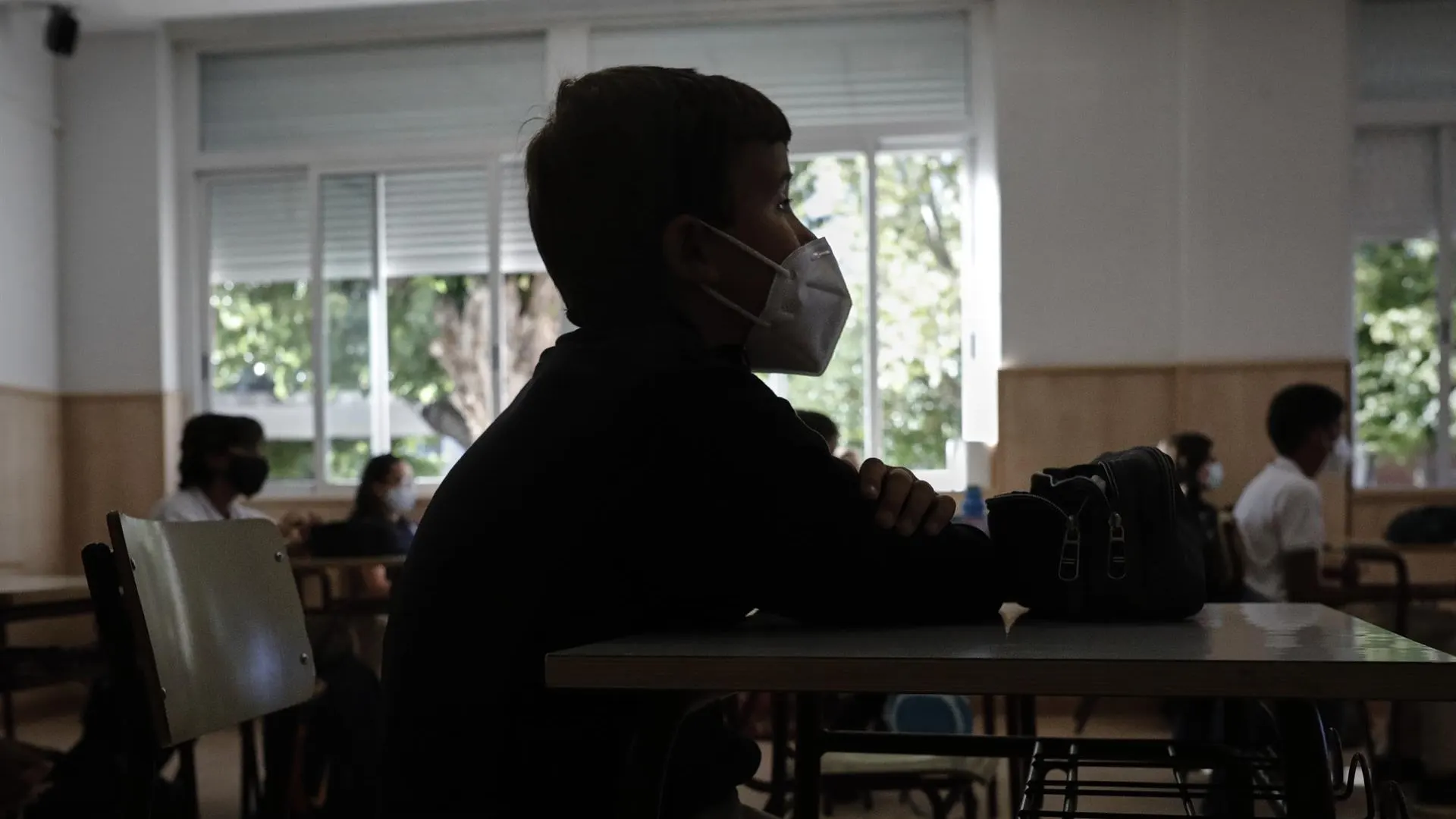 Un niño con mascarilla en un aula. 