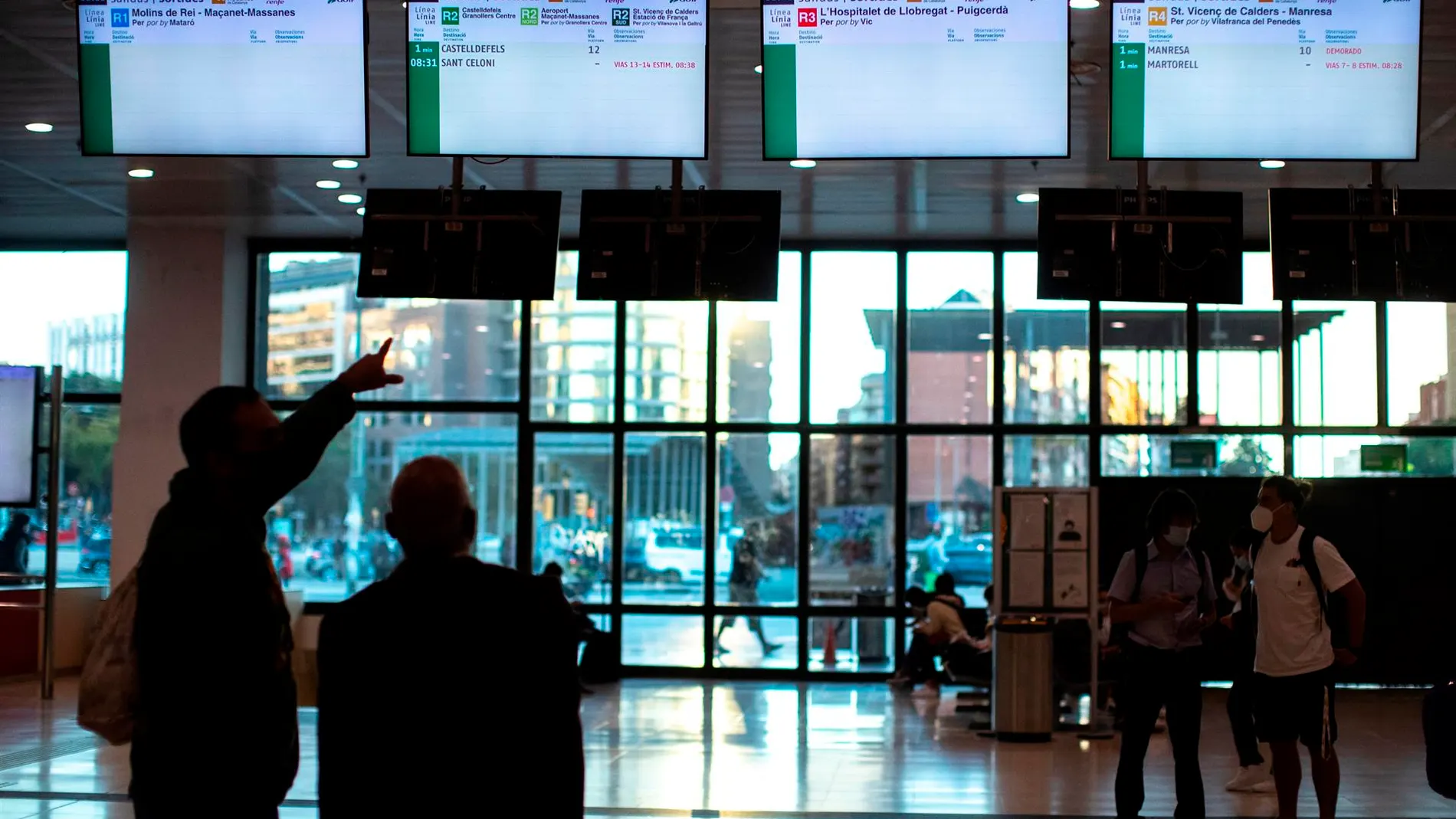 Varios usuarios de Renfe esperan n el vestíbulo de la estación de Sants a que aparezca información sobre los horarios de los trenes.