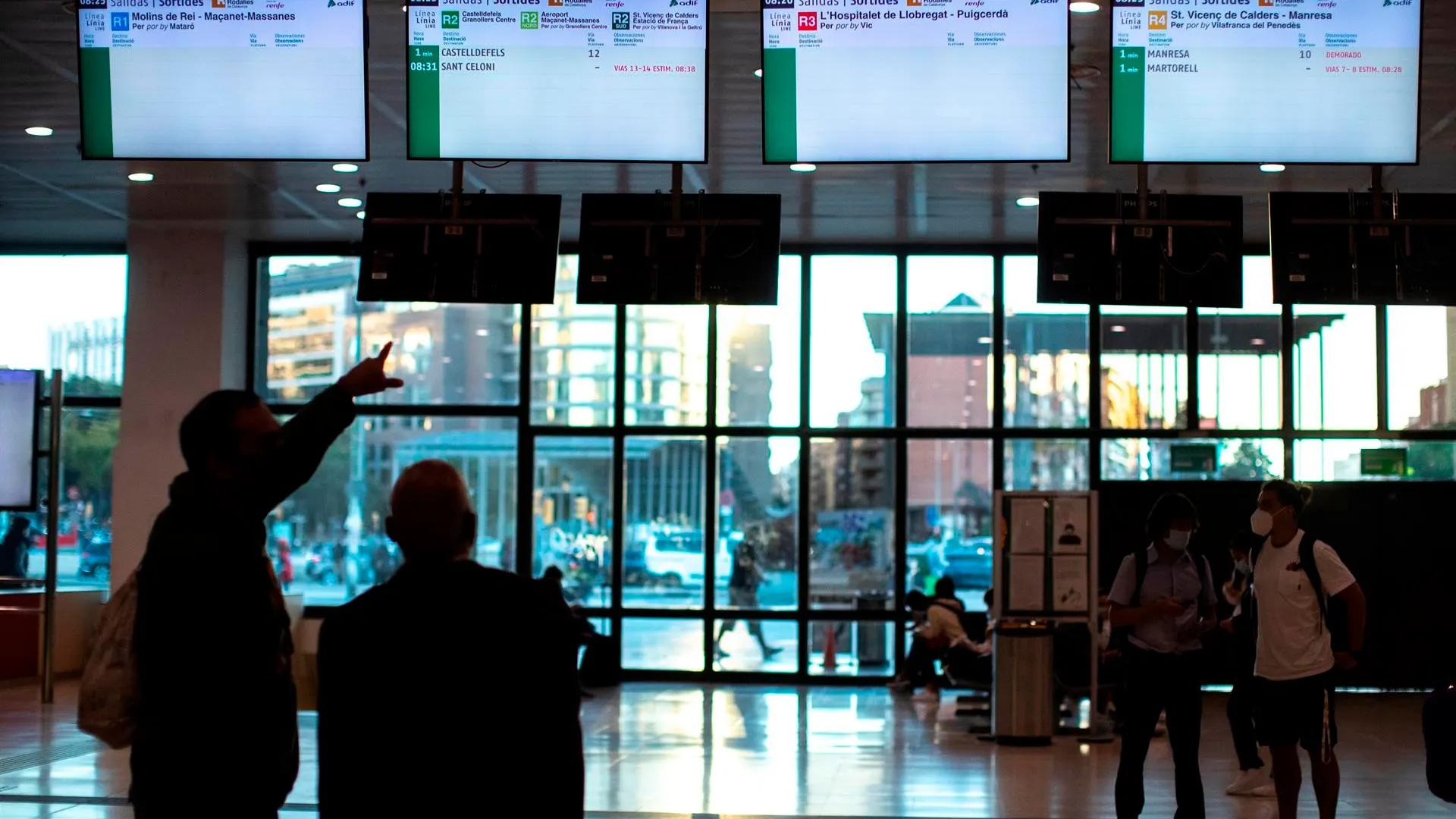 Varios usuarios de Renfe esperan n el vestíbulo de la estación de Sants a que aparezca información sobre los horarios de los trenes.