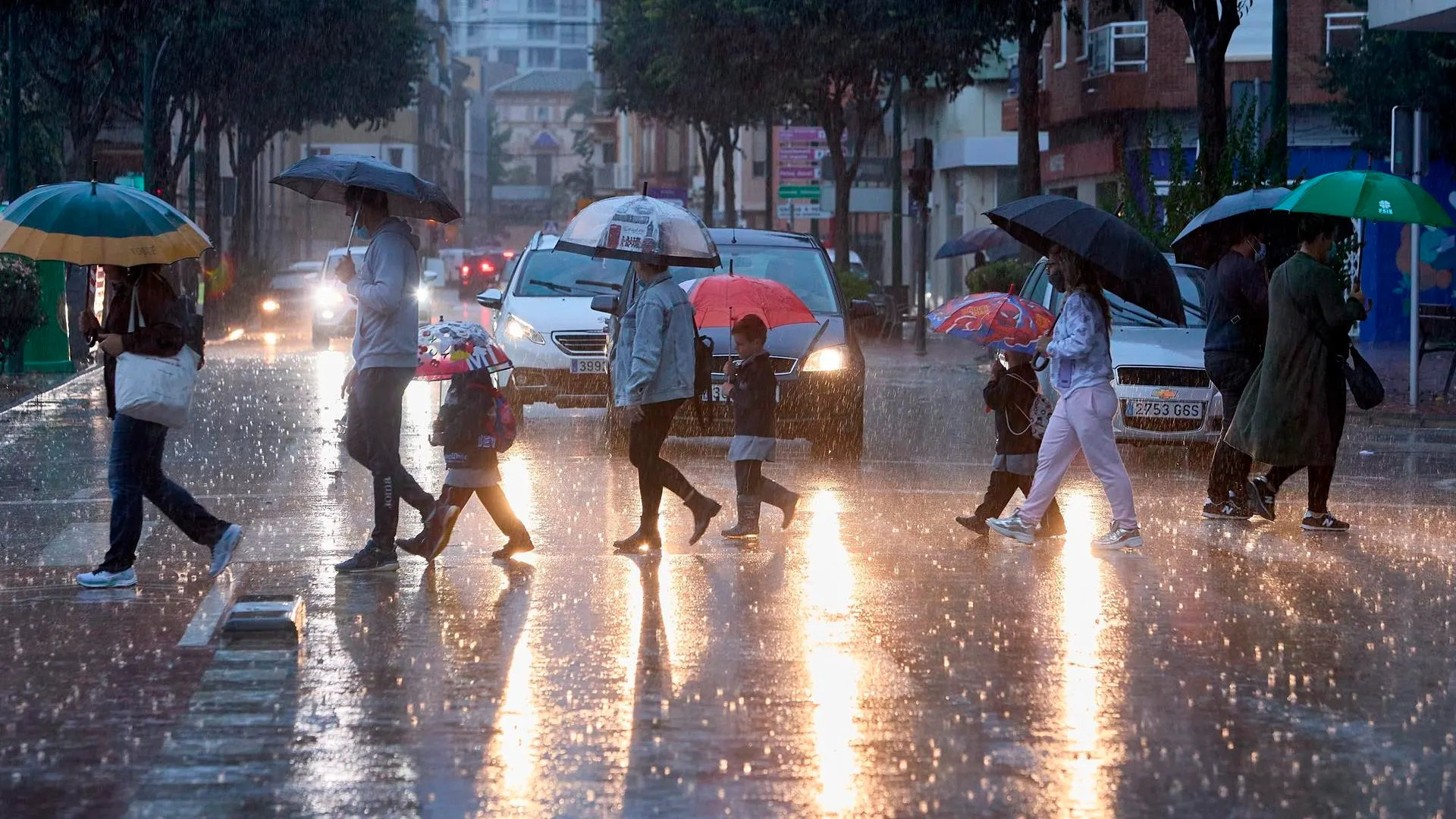 Varias personas cruzan una calle bajo la lluvia