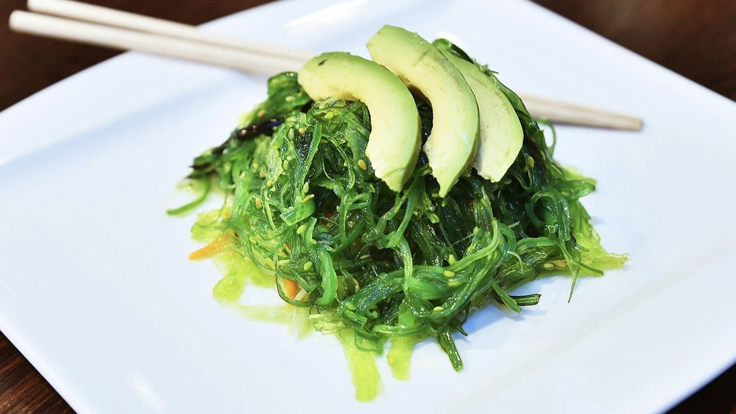 Imagen de archivo de un plato con alga wakame y rodajas de aguacate Imagen de archivo de un plato con alga wakame y rodajas de aguacate