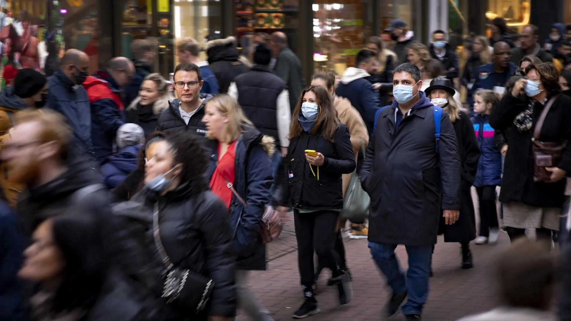 Varias personas en una calle céntrica de Ámsterdam llevando mascarillas por la pandemia de coronavirus