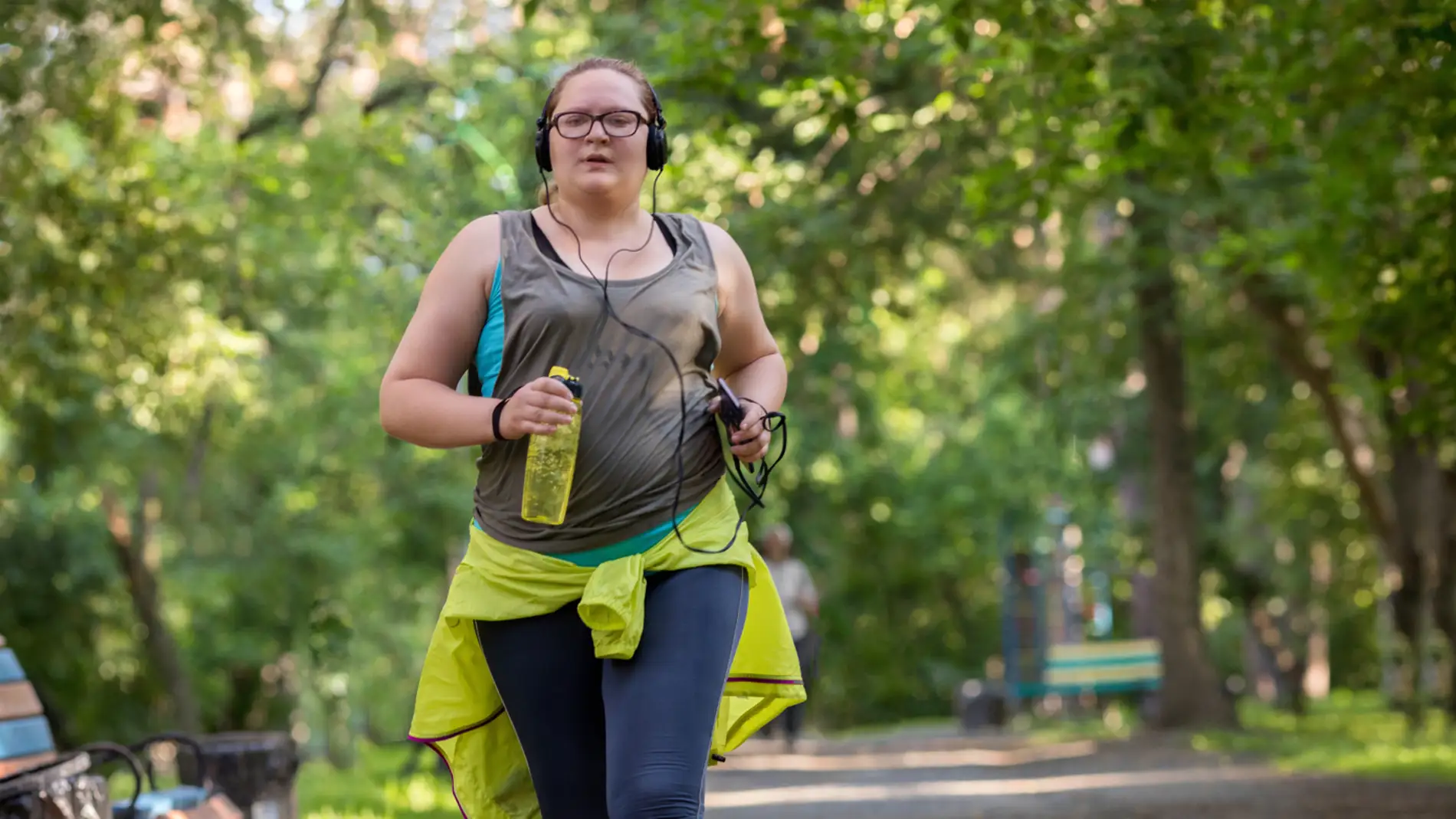 mujer con sobrepeso corriendo por un parque