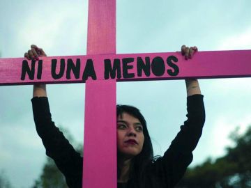 Una joven sujeta una cruz de color rosa durante una concentración contra la violencia machista