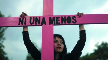 Una joven sujeta una cruz de color rosa durante una concentración contra la violencia machista