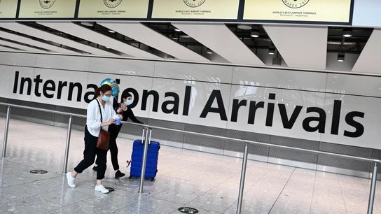 Dos pasajeros con mascarilla en el interior de un aeropuerto Dos pasajeros con mascarilla en el interior de un aeropuerto