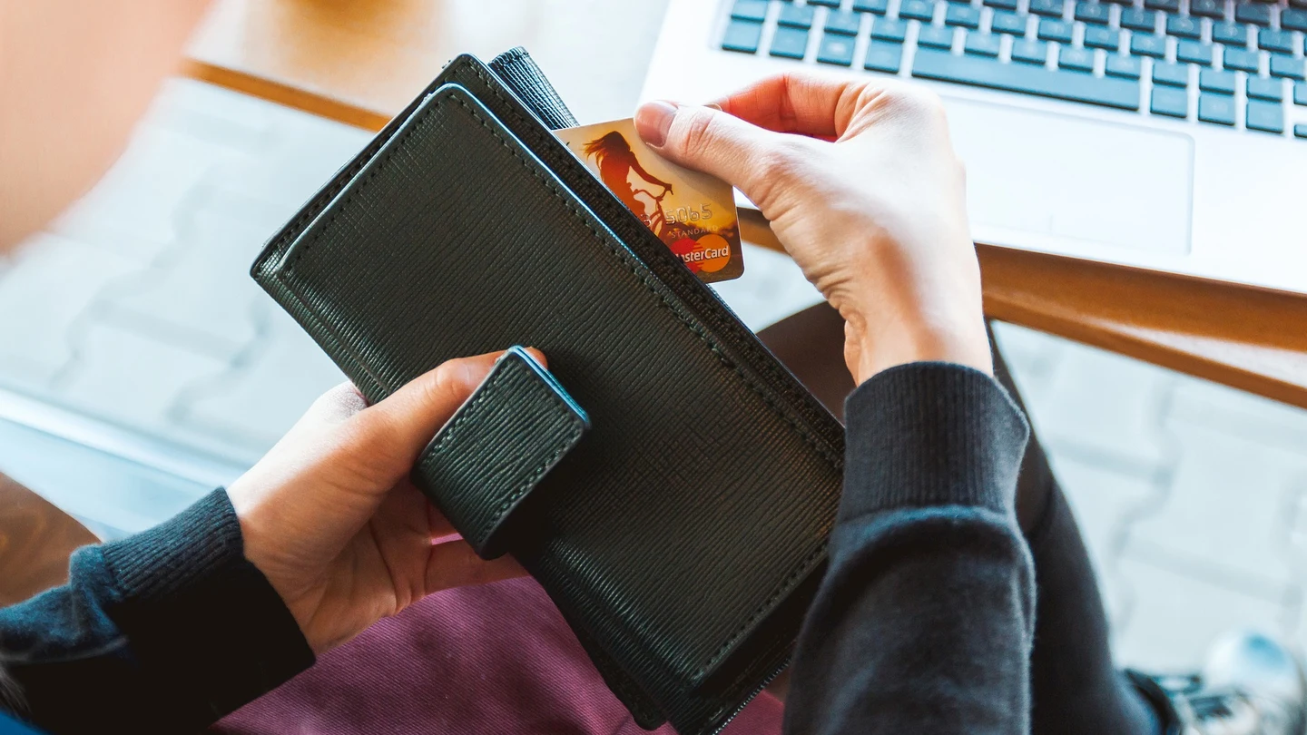 Una persona saca una tarjeta de crédito de su cartera Una persona saca una tarjeta de crédito de su cartera