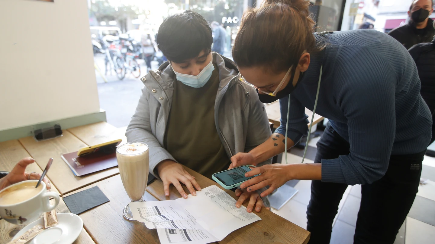 Un camarero comprueba el pasaporte COVID de un cliente en un bar del barrio de Gracia de Barcelona. Un camarero comprueba el pasaporte COVID de un cliente en un bar del barrio de Gracia de Barcelona.