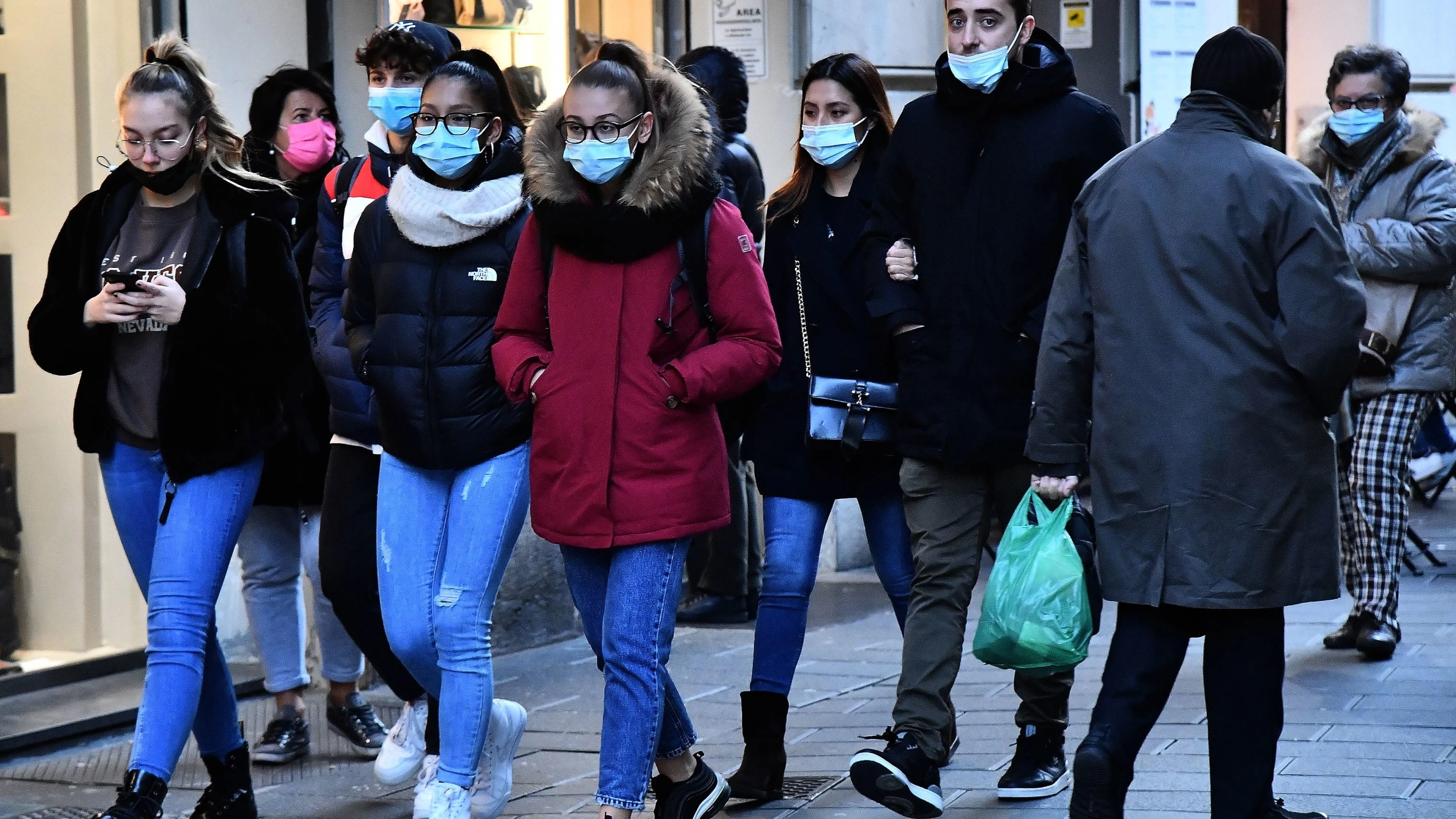 Varias personas pasean por la calle con mascarilla.