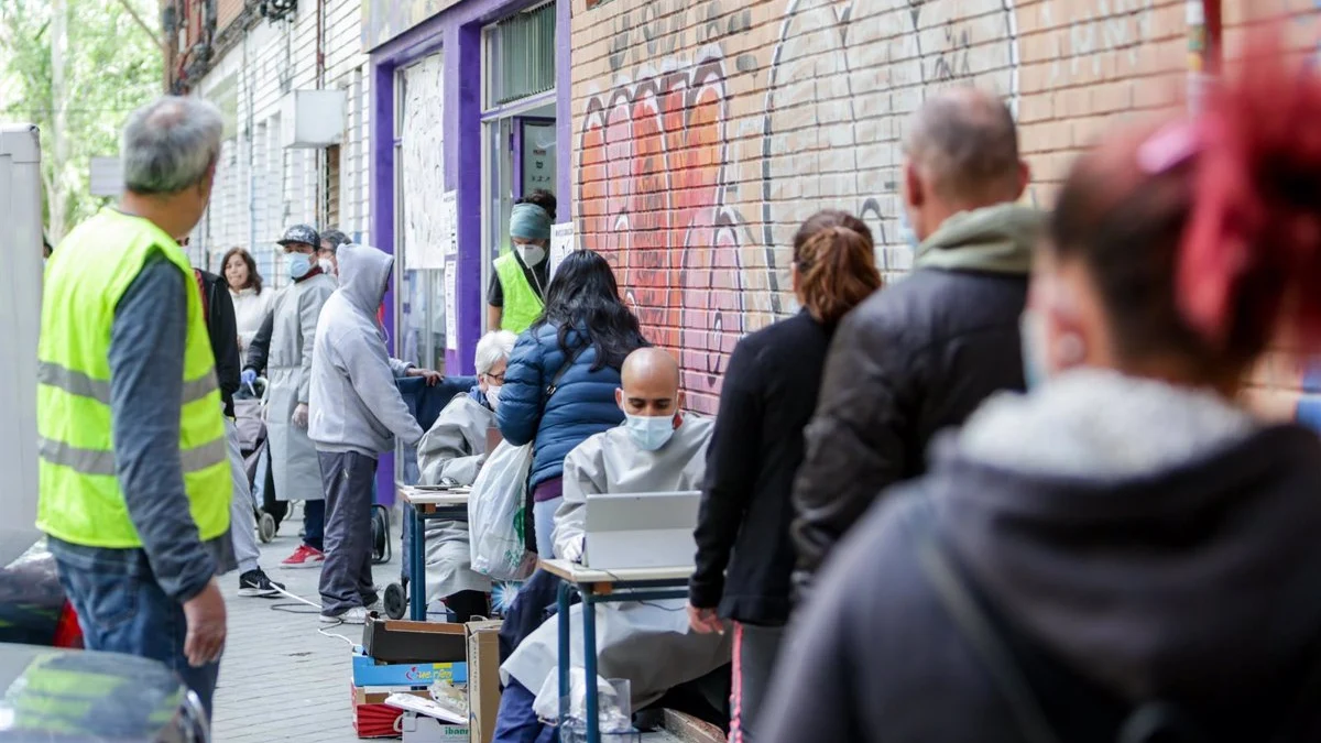 Vecinos realizan una cola para recoger bolsas de la Asociación de Vecinos Parque Aluche