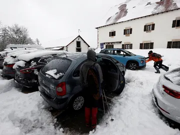 Dos personas empujan un vehículo que ha quedado atrapado en la nieve en el parking de Roncesvalles Dos personas empujan un vehículo que ha quedado atrapado en la nieve en el parking de Roncesvalles