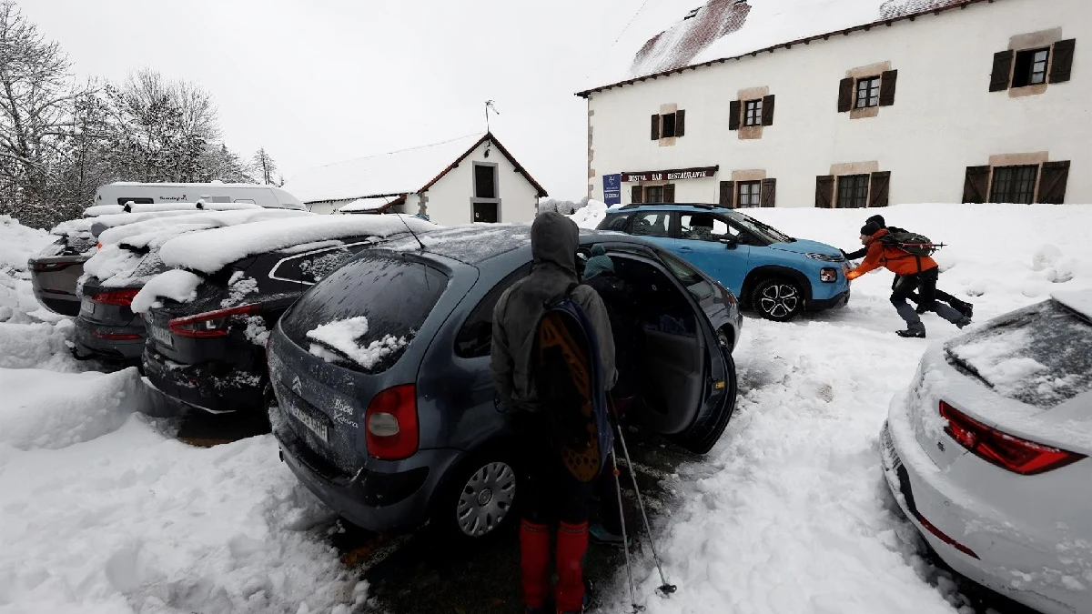 Dos personas empujan un vehículo que ha quedado atrapado en la nieve en el parking de Roncesvalles 