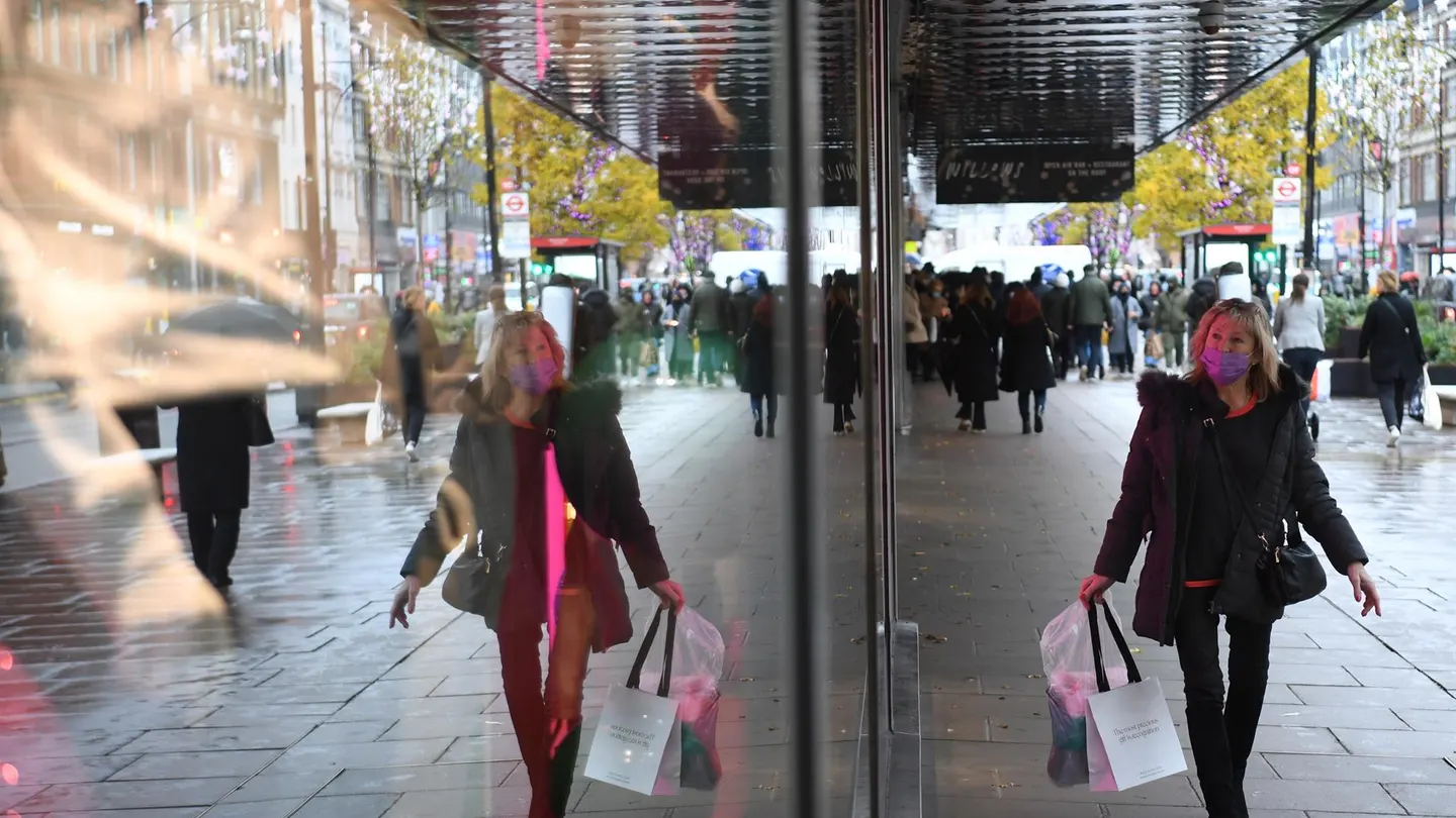 Señora con mascarilla anda por la calle y mira los escaparates de las tiendas Señora con mascarilla anda por la calle y mira los escaparates de las tiendas
