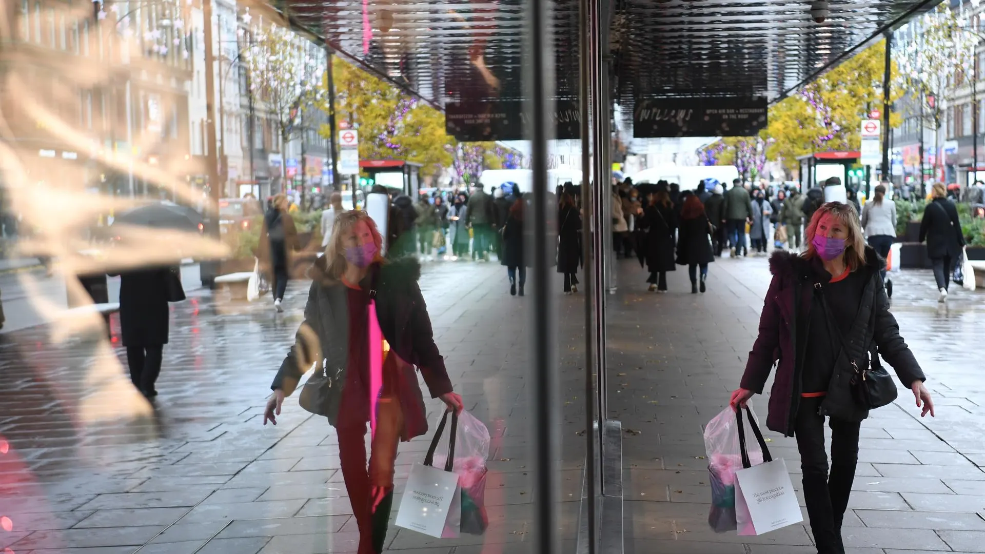 Señora con mascarilla anda por la calle y mira los escaparates de las tiendas