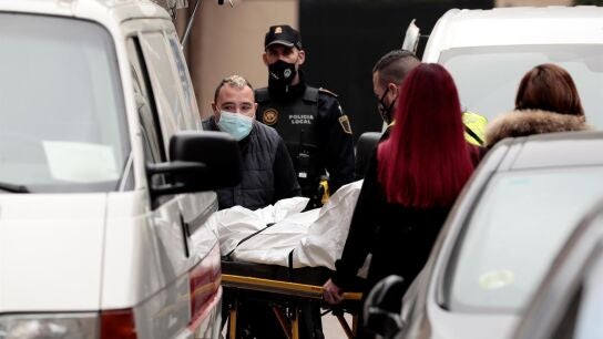 Miembros del ret&eacute;n funebre trasladan el cuerpo del hombre que ha muerto como consecuencia de los martillazos.