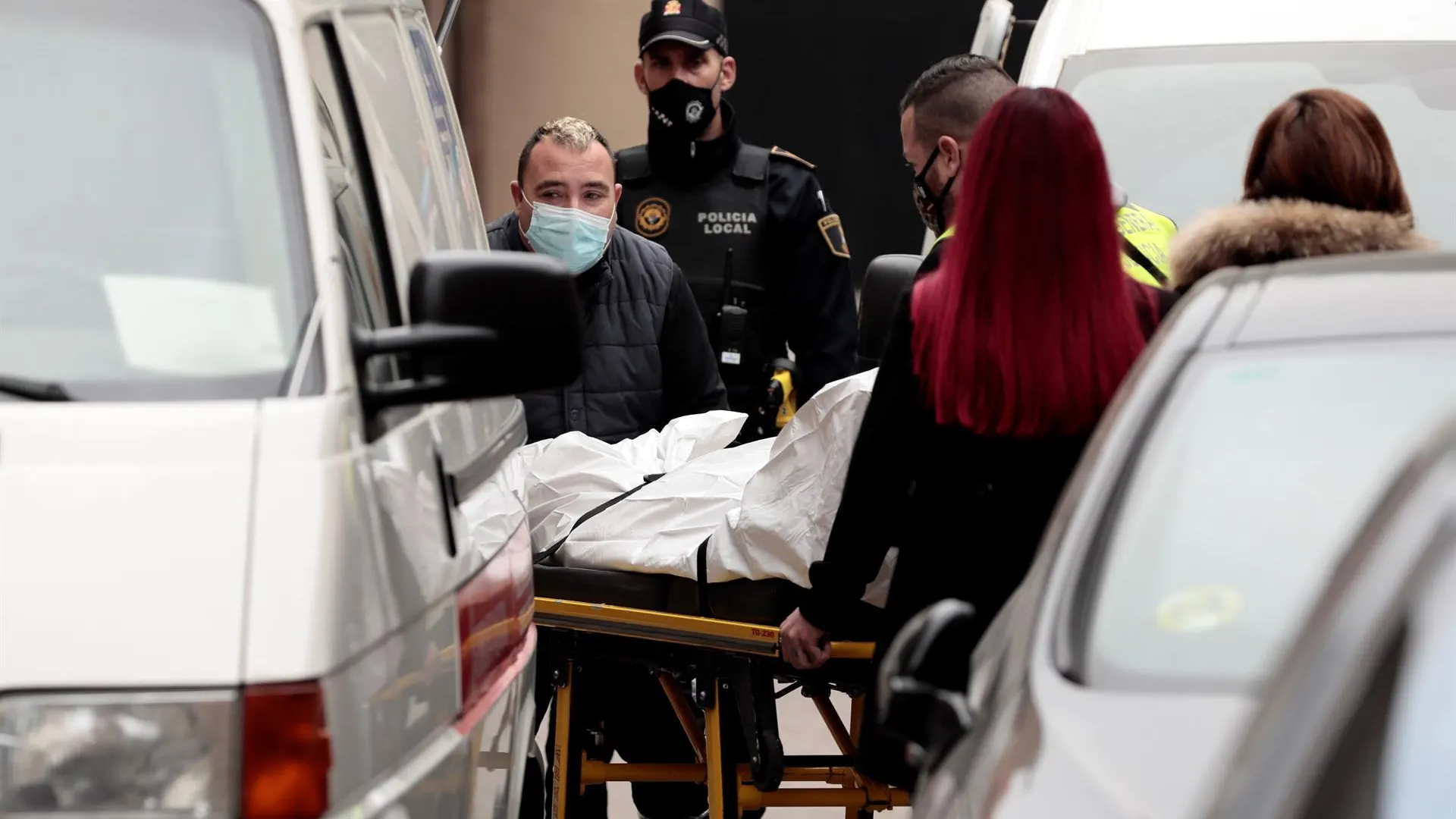 Miembros del retén funebre trasladan el cuerpo del hombre que ha muerto como consecuencia de los martillazos.