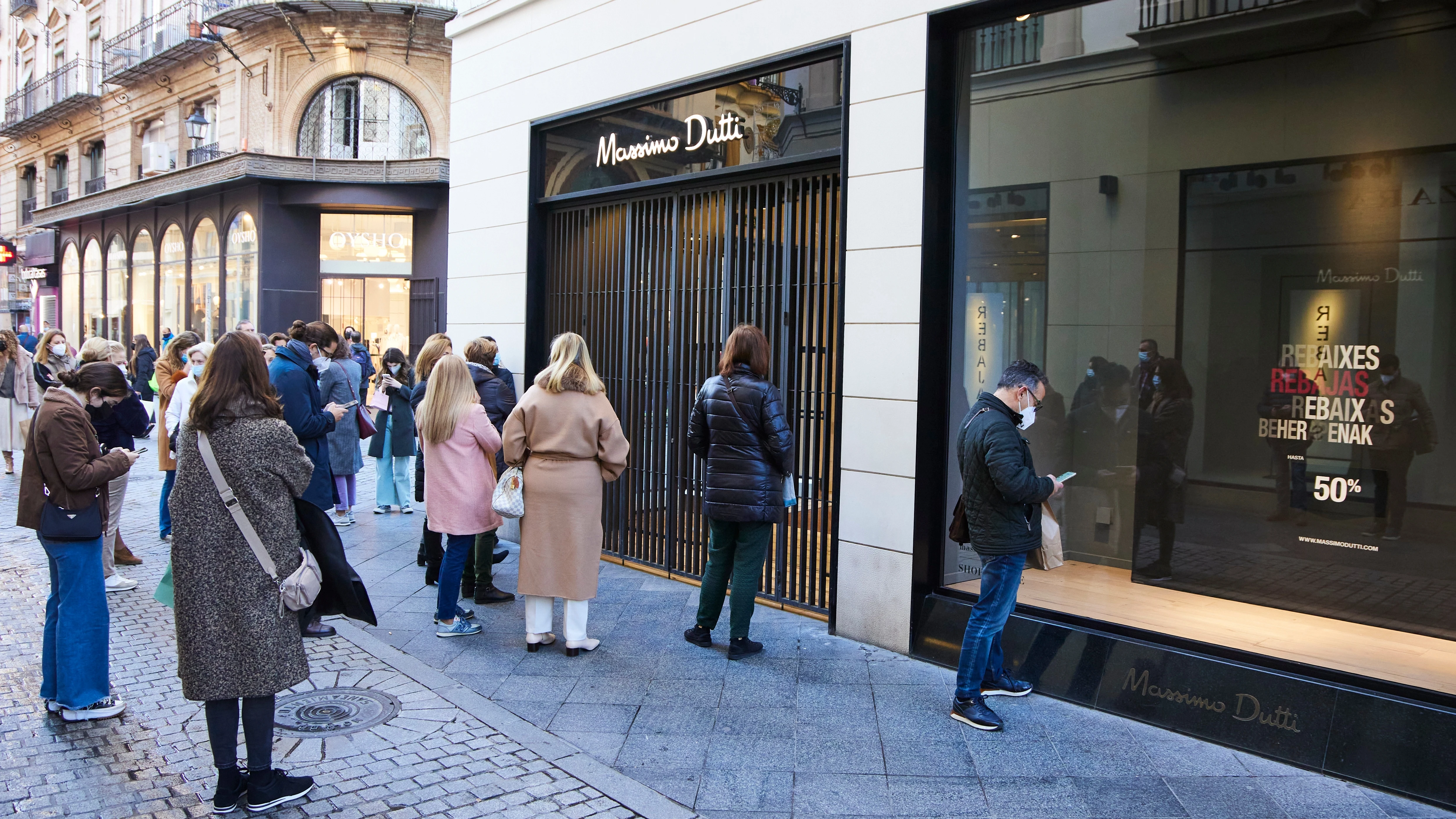 Personas esperan la apertura de los negocios durante el primer día de las rebajas en Sevilla