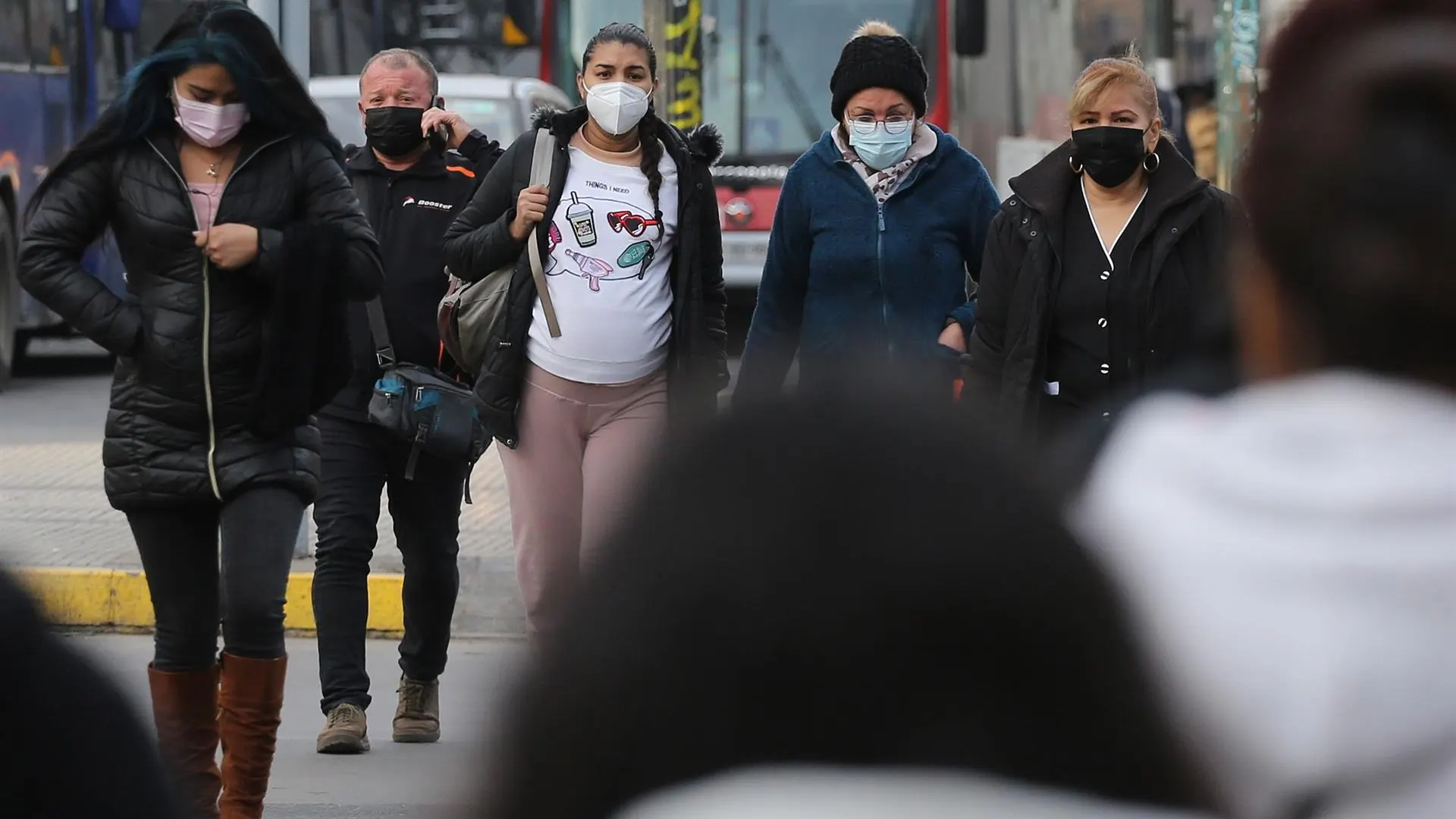 Personas andando por la calle con mascarillas