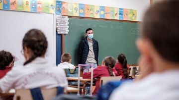 Un profesor da clase con mascarilla a un grupo de niños