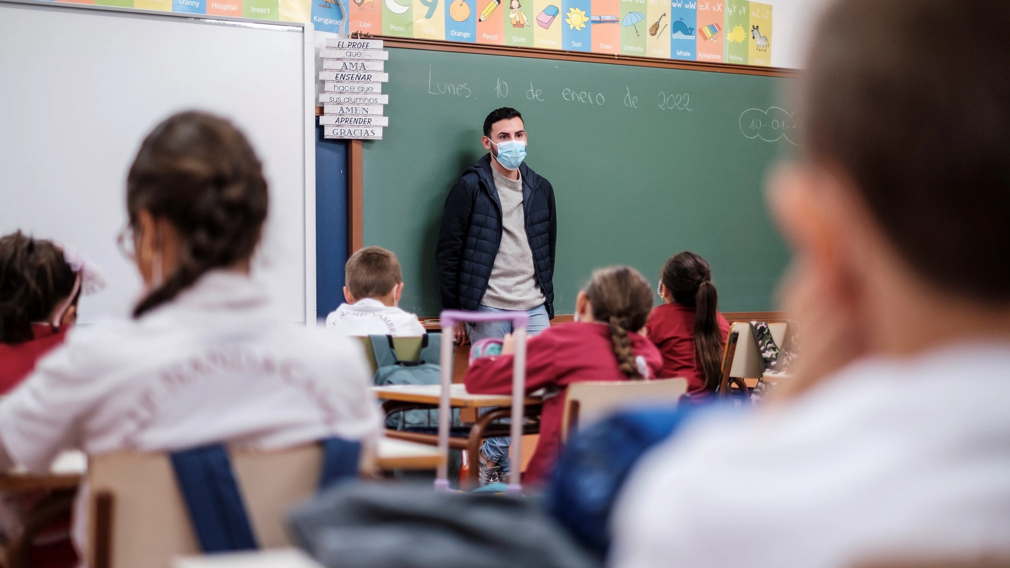 Un profesor da clase con mascarilla a un grupo de niños