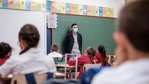 Un profesor da clase con mascarilla a un grupo de niños