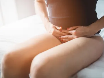 Una mujer se lleva las manos al vientre Una mujer se lleva las manos al vientre