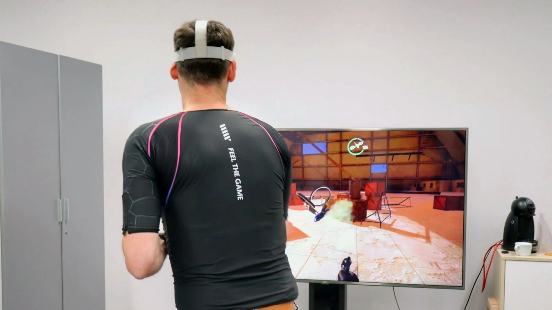 Un voluntario juega a un videojuego con la chaqueta que permite al jugador percibir en su piel las sensaciones de los personajes que maneja en el mundo virtual, en Málaga.