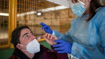 Una trabajadora sanitaria ayuda a un joven a realizarse un test de antígenos en Ribadavia, en Ourense