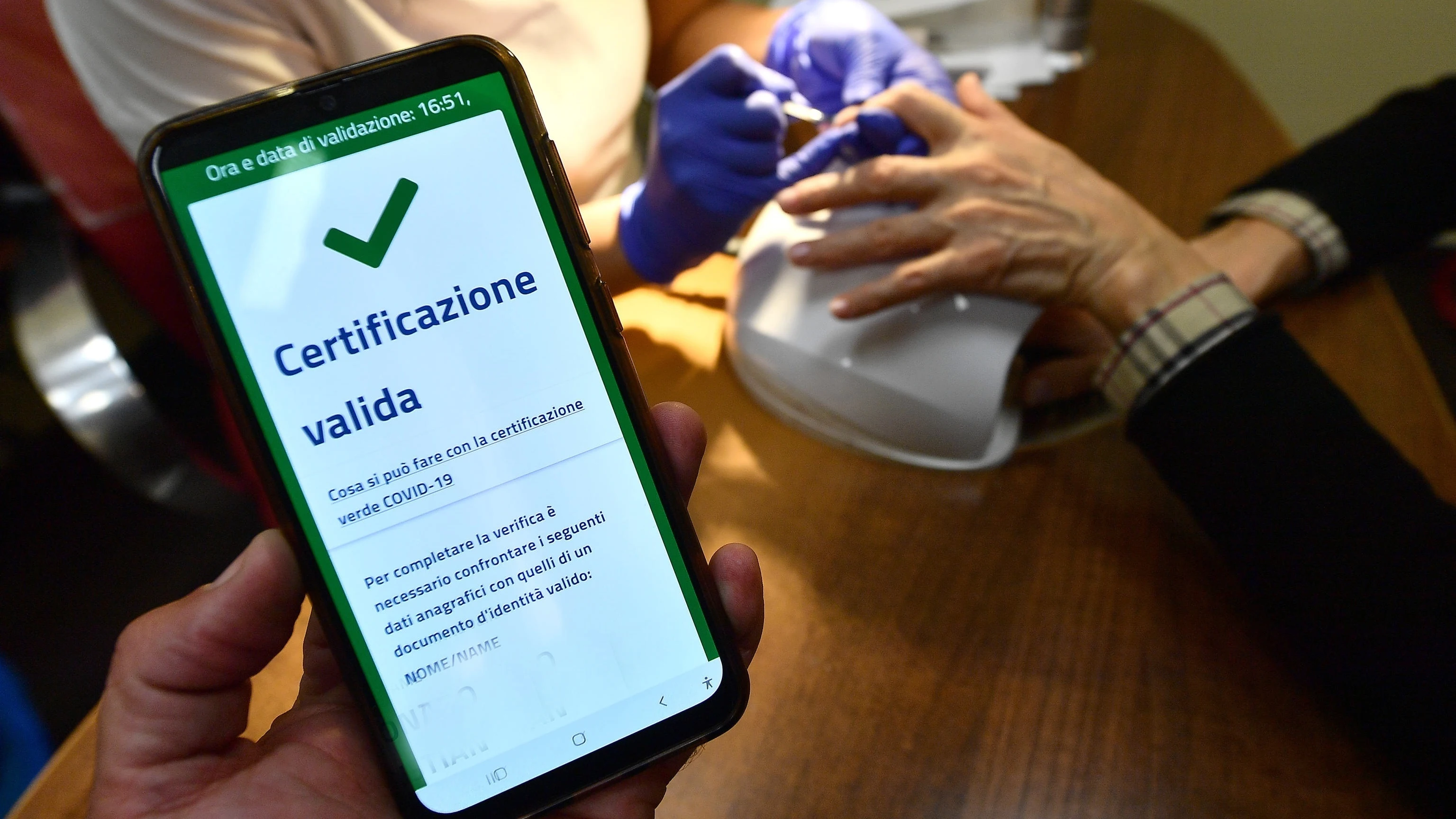 Una persona muestra su certificado COVID en un centro de estética en Génova, Italia