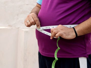 Un hombre mide la circunferencia de su barriga