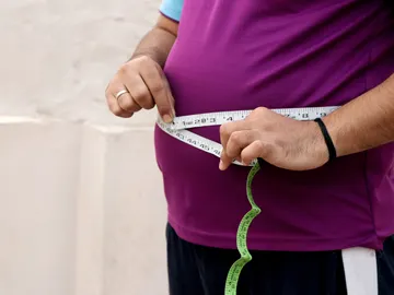 Un hombre mide la circunferencia de su barriga Un hombre mide la circunferencia de su barriga