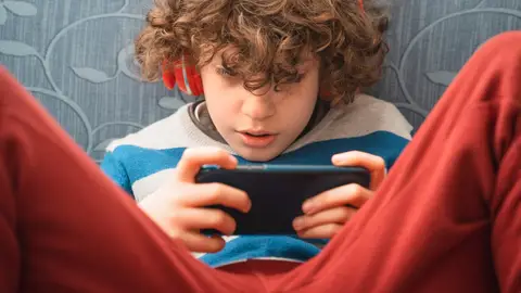 Un adolescente con auriculares y su móvil. Un adolescente con auriculares y su móvil.