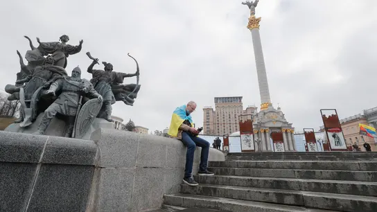 Un hombre, envuelto en la bandera ucraniana, consulta su teléfono móvil en la plaza de la Independencia en Kiev, la capital del país. Un hombre, envuelto en la bandera ucraniana, consulta su teléfono móvil en la plaza de la Independencia en Kiev, la capital del país.