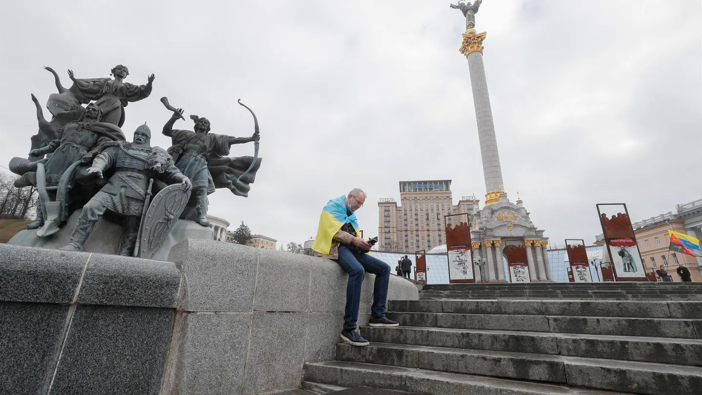 Un hombre, envuelto en la bandera ucraniana, consulta su teléfono móvil en la plaza de la Independencia en Kiev, la capital del país. Un hombre, envuelto en la bandera ucraniana, consulta su teléfono móvil en la plaza de la Independencia en Kiev, la capital del país.