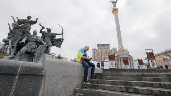 Un hombre, envuelto en la bandera ucraniana, consulta su tel&eacute;fono m&oacute;vil en la plaza de la Independencia en Kiev, la capital del pa&iacute;s.