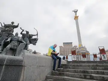 Un hombre, envuelto en la bandera ucraniana, consulta su teléfono móvil en la plaza de la Independencia en Kiev, la capital del país.