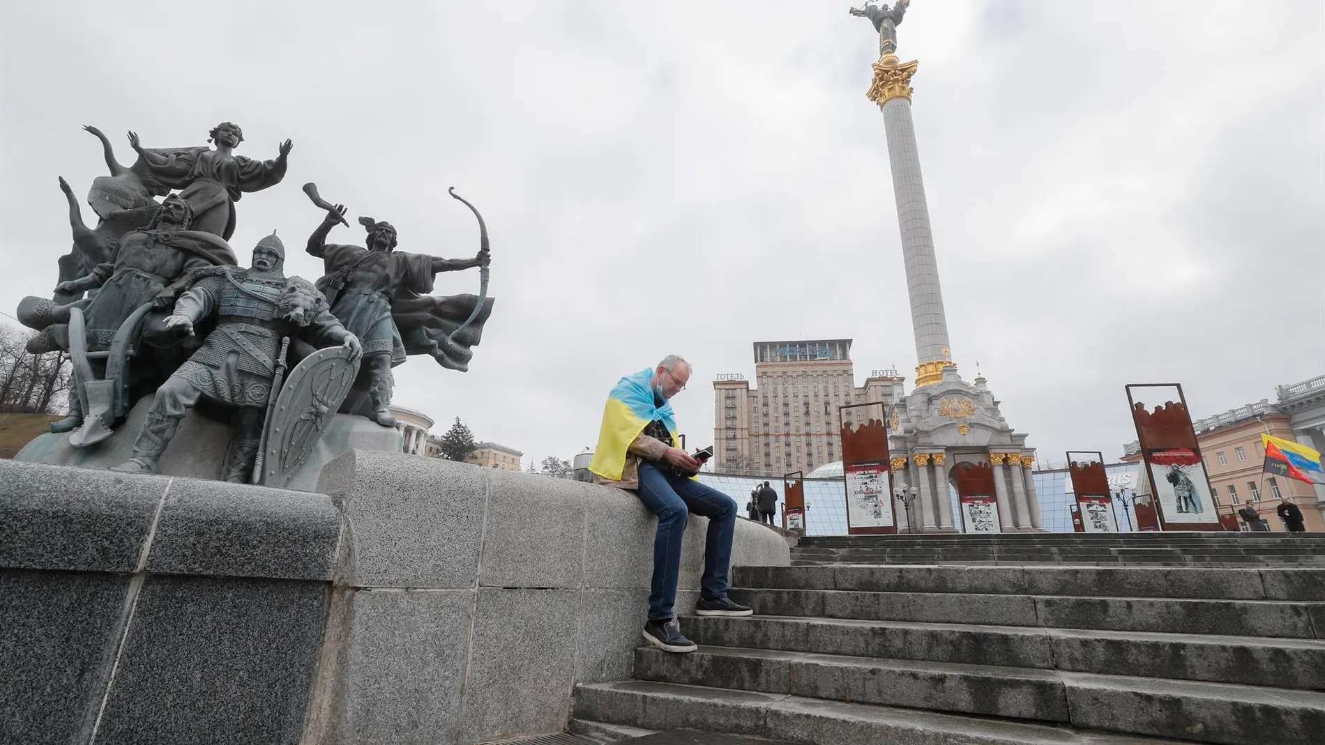 Un hombre, envuelto en la bandera ucraniana, consulta su teléfono móvil en la plaza de la Independencia en Kiev, la capital del país.