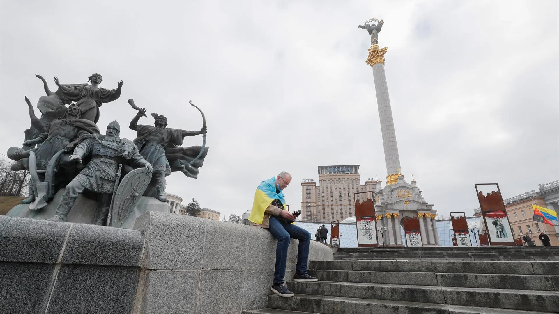 Un hombre, envuelto en la bandera ucraniana, consulta su teléfono móvil en la plaza de la Independencia en Kiev, la capital del país.