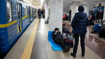 Un hombre trata de descansar sobre una colchoneta en una estación de metro