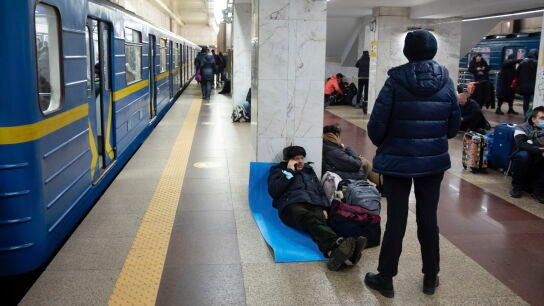 Un hombre trata de descansar sobre una colchoneta en una estación de metro